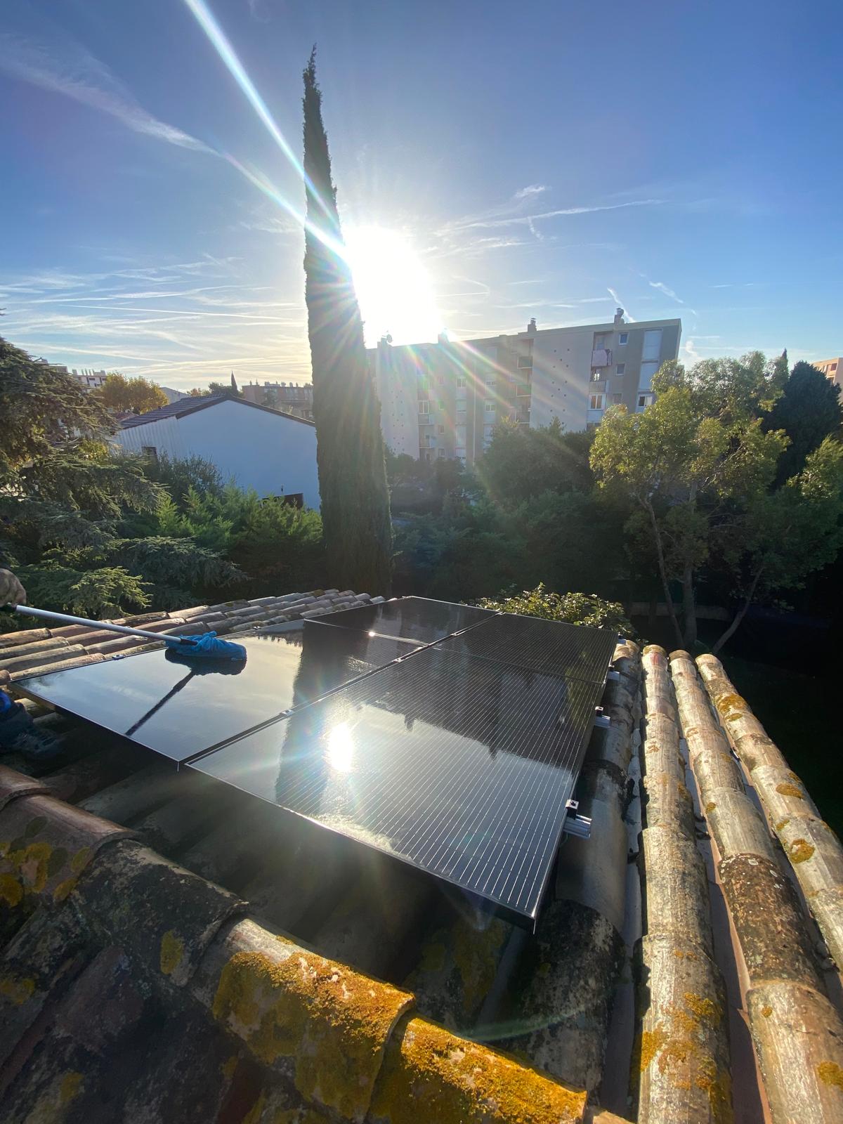Brosse de nettoyage sur des panneaux photovoltaïques installés sur une toiture en tuiles